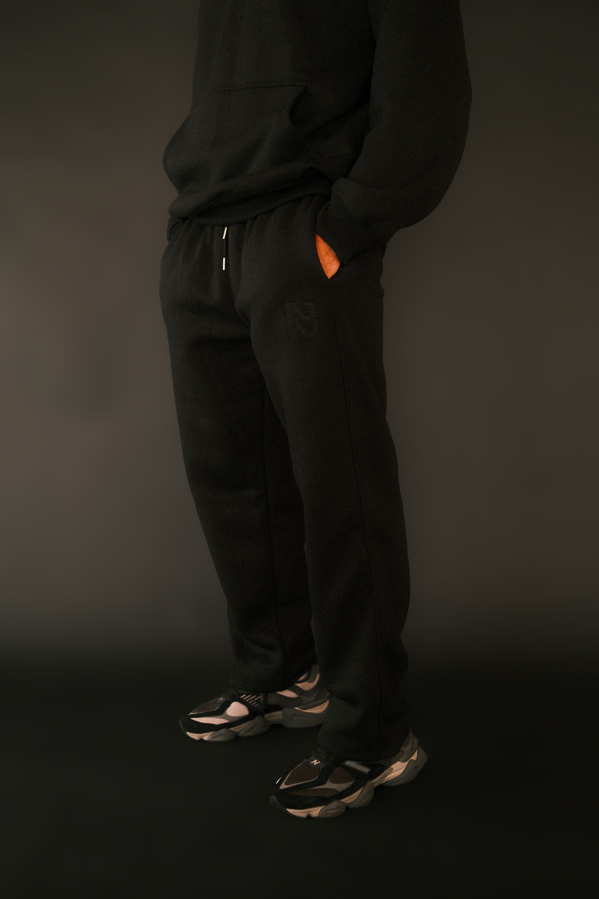 Person wearing black pants and shoes on a dark background